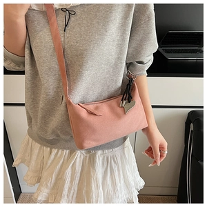 Détail du sac bandoulière rose avec un pendentif en cœur argenté et texture en daim doux