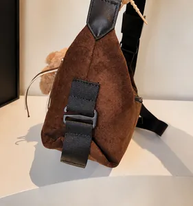 Détail de l'attache en D et de la texture en daim marron sur ce sac à bandoulière chic