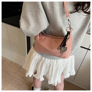 Détail du sac à bandoulière en daim rose avec pendentif coeur argenté et sangle réglable