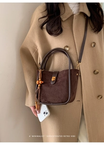 Detail einer braunen Retro-Eimertasche aus Wildleder mit Holzperlenquaste und Goldverschluss