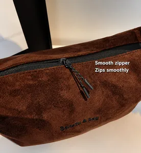 Détail de la fermeture éclair en métal noir et de la tirette tissée sur le sac en daim café