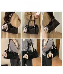 Detail view of large black tote bag with silver buckle and plush rabbit pendant