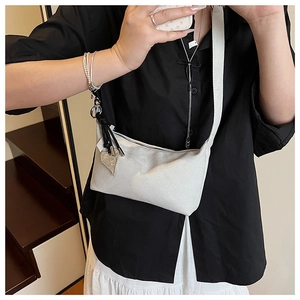 Détail du sac oreiller en daim gris clair avec breloque cœur et pompon noir chic