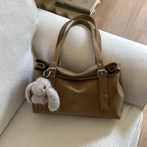 Detail of caramel brown tote bag with silver hardware and a plush rabbit charm