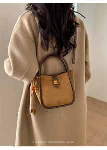 Detail der Vintage-Eimertasche aus braunem Wildleder mit goldenem Drehverschluss und Quaste