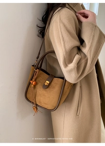 Detail der Retro-Wildleder-Beuteltasche mit goldenem Drehverschluss und Holzperlen-Quaste