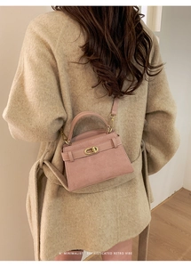 Detail of pink matte suede handbag with golden twist-lock and beige cashmere coat context