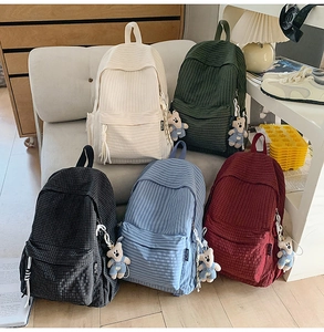 Detail showing the ribbed corduroy texture and plush bear charm on colorful backpacks