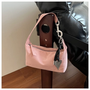 Détail de la texture suédée rose mat et du pendentif coeur en métal sur le sac à main