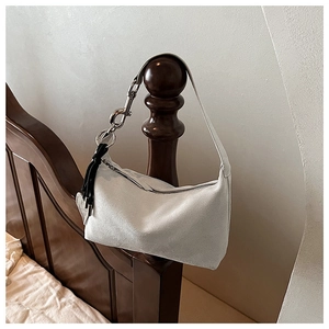 Détail du sac oreiller en daim avec boucle en argent et charm cœur à pompon noir élégant