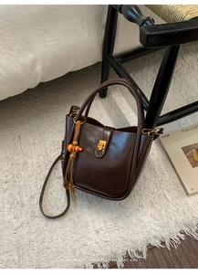 Detailansicht dunkelbraune Retro-Lederhandtasche mit Goldschnalle und Holzperlen-Quaste
