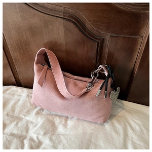 Détail du sac oreiller en daim rose avec pendentif en cœur et pompon tissé noir chic