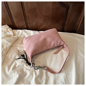 Détail du sac oreiller en daim rose clair avec fermeture éclair argentée et breloque en cœur