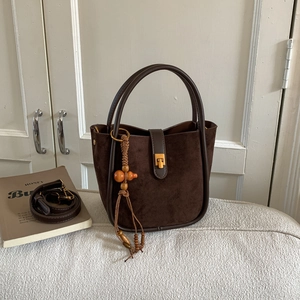 Nahaufnahme der dunkelbraunen Retro-Wildledertasche mit Holzperlenquaste und Schnalle