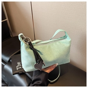 Détail du sac demi-lune en daim vert menthe avec fermeture éclair et breloque en cœur
