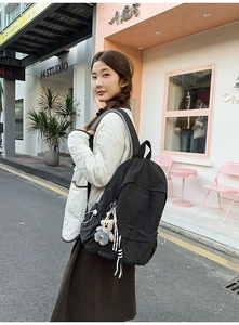 Detail view of a plaid canvas backpack with a cute bear charm pendant on the street