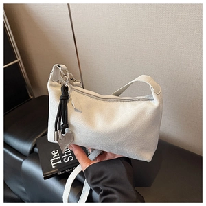 Détail du sac oreiller en daim blanc avec pendentif coeur et bandoulière tissée