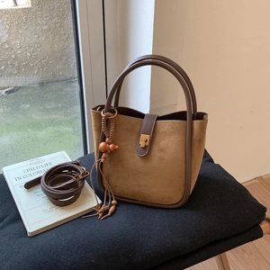 Detailansicht der braunen Wildleder-Beuteltasche mit Goldschließe und Vintage-Perlenanhänger