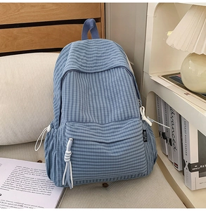 Detailed view of blue gingham backpack with zipper pocket and decorative white tassel