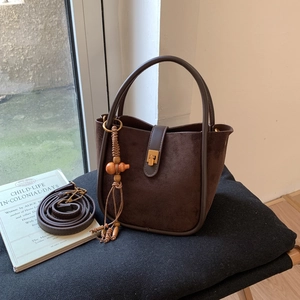 Detail einer braunen Wildleder-Beuteltasche mit Ledergriff und goldenem Verschluss
