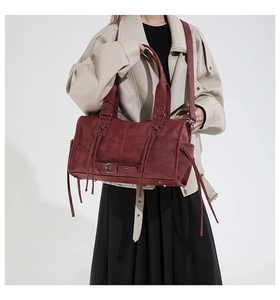 Details einer burgunderroten Vintage-Tasche mit Lederquasten und Schnallenriemen