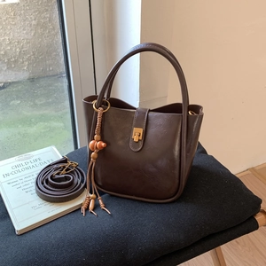 Detail einer dunkelbraunen Vintage-Beuteltasche mit Gold-Hardware und Perlenquasten