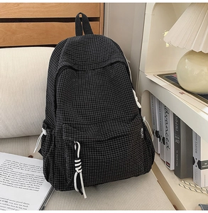 Close-up of black and white checkered backpack fabric with detailed zipper pull and side label