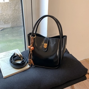 Detail der schwarzen Vintage Beuteltasche mit poliertem Finish, Goldverschluss und Quaste