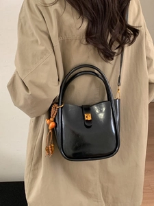 Elegante schwarze glänzende Lederhandtasche mit Gold-Schnalle und Perlen-Quasten-Anhänger