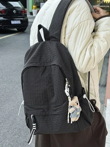 Plaid school backpack with cute bear charm shown in a lifestyle street view setting
