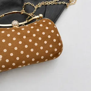 Macro detail of brown polka dot suede bag with golden ring handle and crystal ball