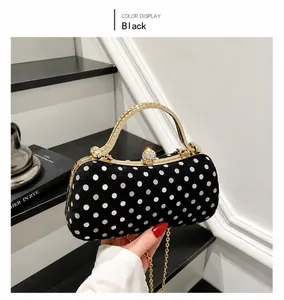 Detail of elegant black velvet polka dot handbag with gold chain and rhinestone clasp