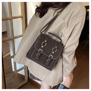 Détail d'un cartable vintage marron foncé avec surpiqûres et boucles métalliques