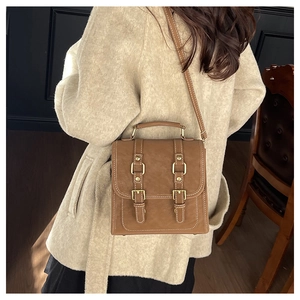 Gros plan du sac à main vintage en cuir marron avec double boucle et surpiqûres contrastées