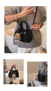 Détail du sac seau noir avec pendentif ours en peluche et poignées rondes vernies