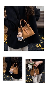 Détail d'un sac seau vintage marron avec charm ours sur des feuilles d'automne