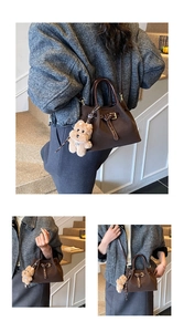 Détail du sac seau en cuir marron foncé avec charm ours en peluche et bandoulière réglable