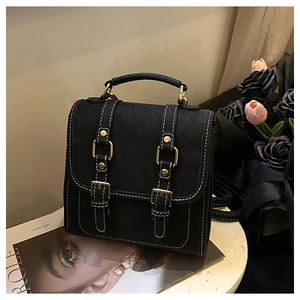 Gros plan du sac à dos rétro noir avec coutures contrastées blanches et boucles dorées