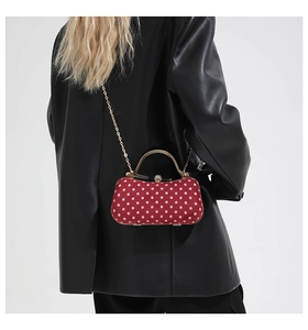 Detail of red and white polka dot box bag with gold chain strap and crystal clasp