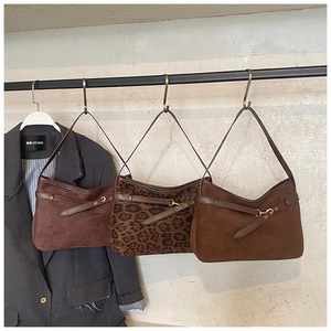 Detail of suede bucket bags in brown and leopard print with metal hardware and strap