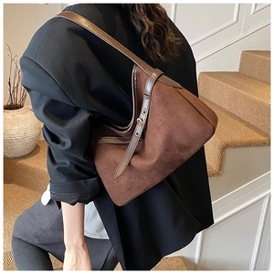Deep brown suede hobo bag shown worn over the shoulder in a minimalist luxury setting