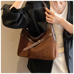 Detail of dark brown suede shoulder bag with leather straps and metal buckle detail