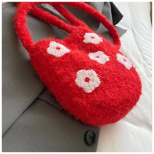 Close-up of red plush bucket bag featuring white 3D floral embroidery and fuzzy texture
