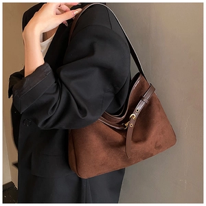 Macro shot of dark brown suede shoulder bag featuring a leather strap with gold eyelet