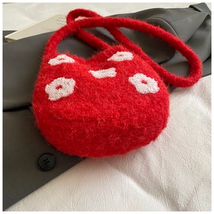 Close-up of fluffy red bucket bag with white floral embroidery and soft plush texture