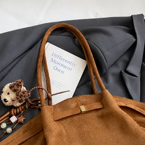 Nahaufnahme der braunen Wildledertasche mit goldener Metallschnalle und Leoparden-Anhänger