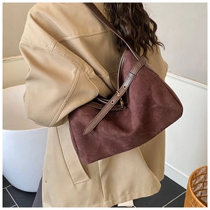 Detail of dark brown suede shoulder bag featuring a strap with gold metal eyelet accents