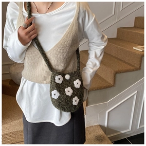 Detail of dark green crochet bucket bag featuring white 3D floral embroidery accents