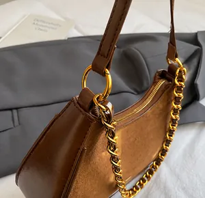 Detalle de bolso hobo marrón con cadena dorada y gancho metálico de alta calidad técnica