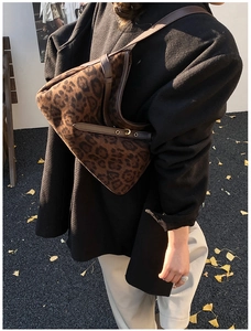 Close-up of leopard print suede shoulder bag with brown leather trim and gold buckles